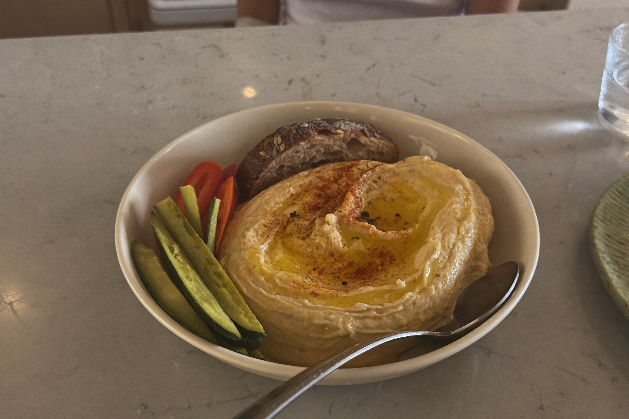 Bol de houmous arrosé d'huile d'olive avec pain complet et légumes
